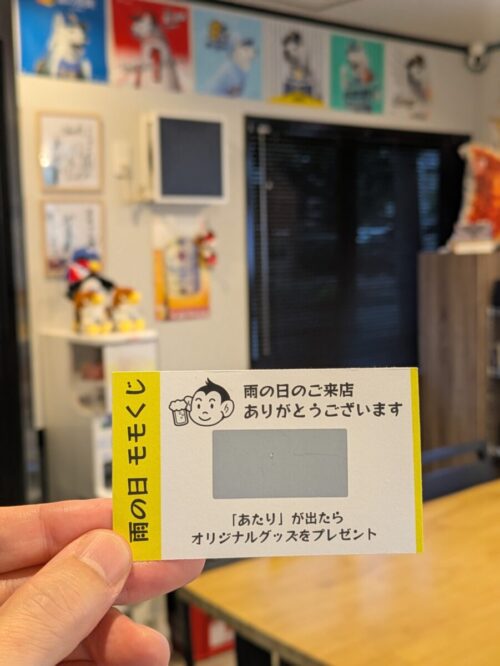 モモタロ店内で手に持った「雨の日 モモくじ」。雨の日のご来店へのお礼と、あたりの景品案内が書かれている