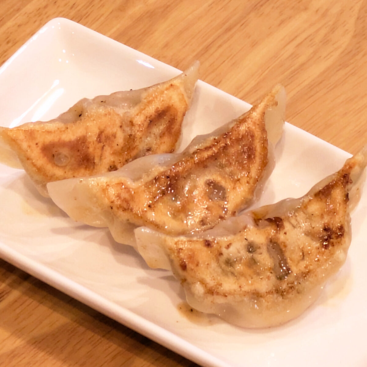 白い皿に並べた、こんがりと焼き色のついたうずら卵の焼き餃子